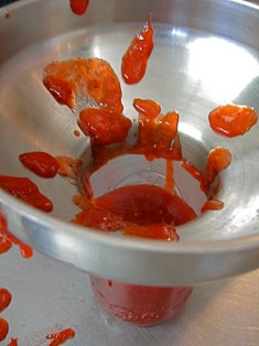 Using a jar funnel to fill a half-pint jar with strawberry jam