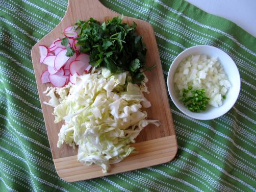 Chicken Pozole fixings: radishes, cilantro, cabbage, onion, serrano, and limes.